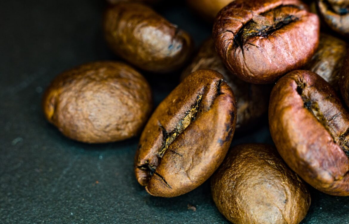 Close-up macro of dark roasted coffee beans with rich brown tones on a black background