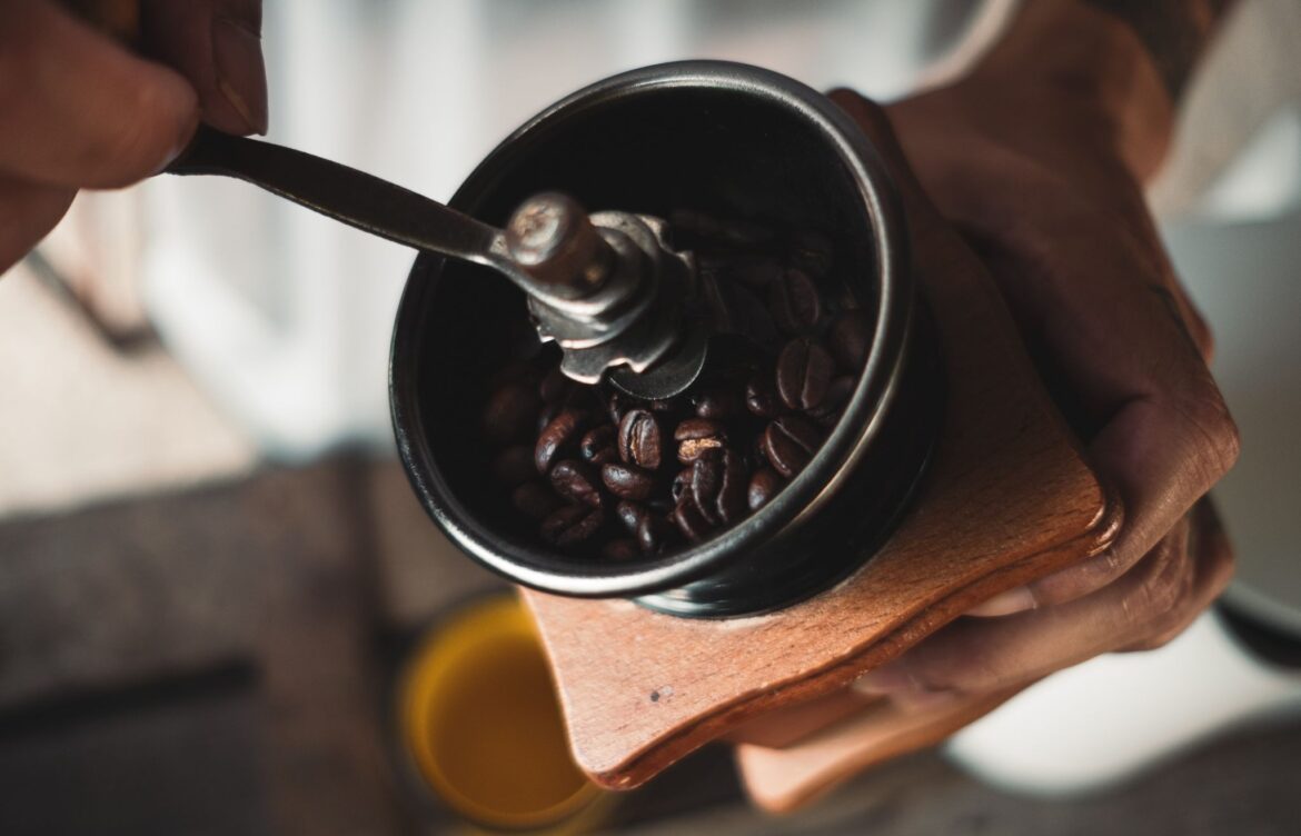 Close-up of hands grinding coffee beans using a manual coffee mill